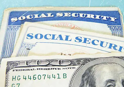 A closeup of a $100 dollar bill and Social Security cards.