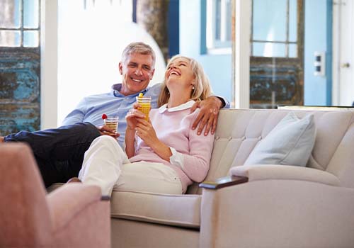 Mature Retired Couple On Couch Laughing Together
