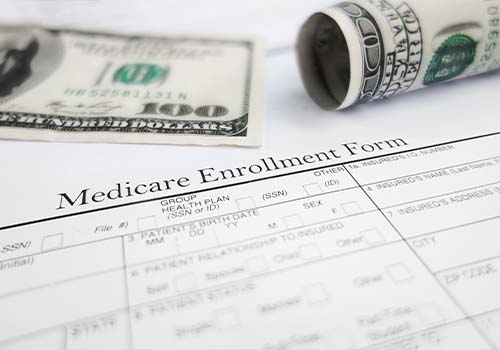 Medicare Enrollment Form With Hundred Dollar Bills In Background