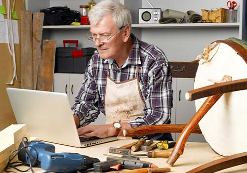 Retired Carpenter Using Laptop From Home Workshop