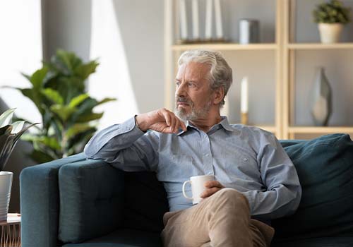 Thoughtful Older Man Sitting On Couch