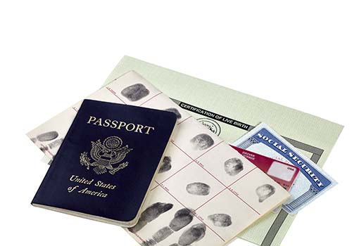 A U.S. passport, fingerprint card, driver's license, , Social Security card, and birth certificate on a white background.