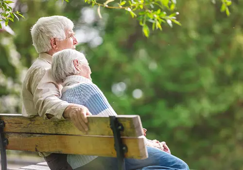 Elderly Couple Resting On A Park Bench