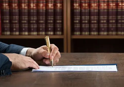 Male Lawyer Writing On Legal Documents At Desk