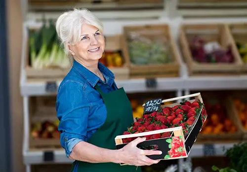 Older Woman Working Holding Box Of Strawberries