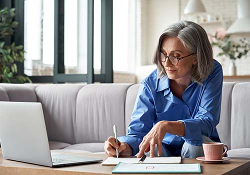 Happy Retired Old Woman Managing Finances On Laptop
