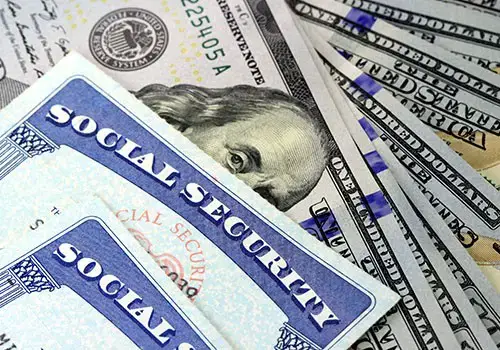 Social security cards on top of hundred dollar bills.