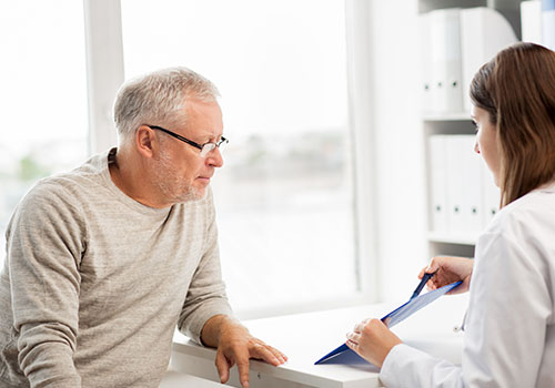 Doctor assisting elderly man with paperwork.