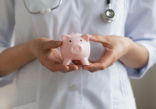 A doctor's hands holding a piggy bank.