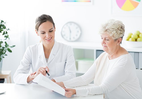 A doctor reviewing paperwork with an elderly female patient.