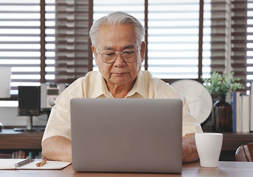 An elderly man using his computer for Medicare Easy Pay.