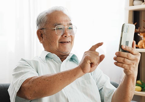 An elderly man using his mobile phone for Medicare Easy Pay.