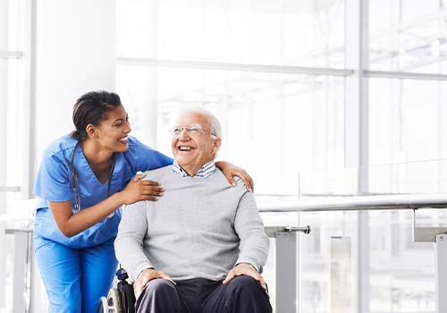 Nurse Assisting Old Man In Wheelchair