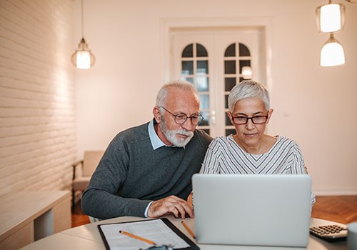 An elderly couple looking at a laptop together.