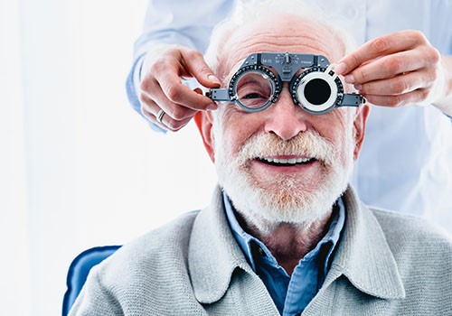 An elderly man gets his eyes checked by an optiician.