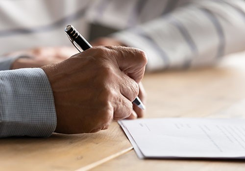 A closeup of a male hand signing a document.