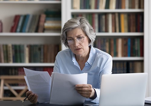An elderly woman looking through paperwork.