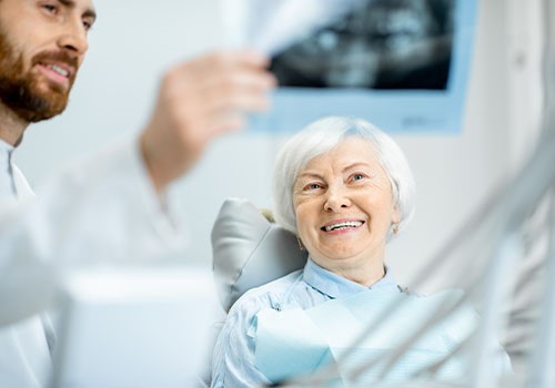 An elderly lady smiling in the dentists chair.