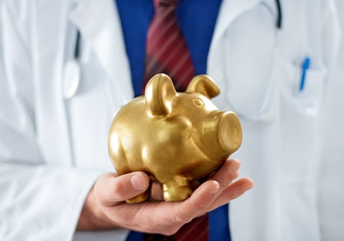 A doctor holding a golden piggy bank.