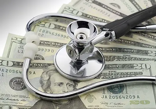 A stethoscope on top of a fanned stack of $20 bills. 