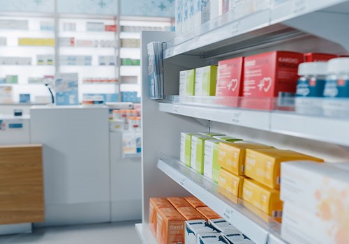Boxes of medication on a pharmacy shelf.