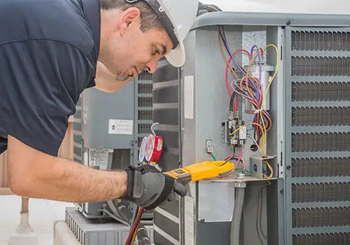 A professional HVAC technician measuring the amperage on an air conditioning unit.