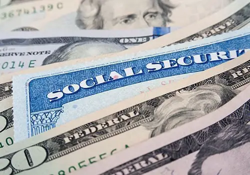 A social security card and cash piled together.