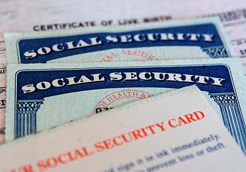 Two social security cards on top of a birth certificate.