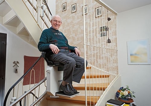 An elderly man using a stairlift in his home.