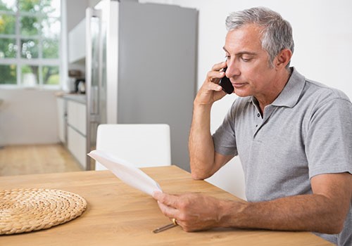 A man on the phone with the SSA to inform them of his earnings while on social security.