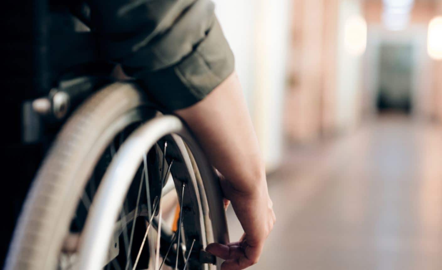 A close-up of a person's hand on a wheelchair wheel.